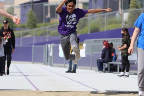 An RCHS special-needs student leaps as far as he can while his teammates cheer him on. 