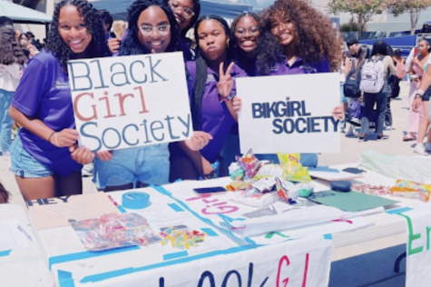 Black Girl Magic Club founders seniors Hannah Hawkins and Lyrique Wilson hold up signs with other club members to get people to come and sign up for the club!
