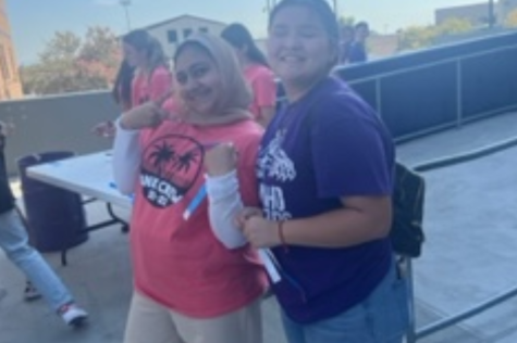 Serving in her role as treasurer of Link Crew, Maala Noor, and fellow senior Leslee Rodriguiz passes out wristbands at the Freshman Tailgate.