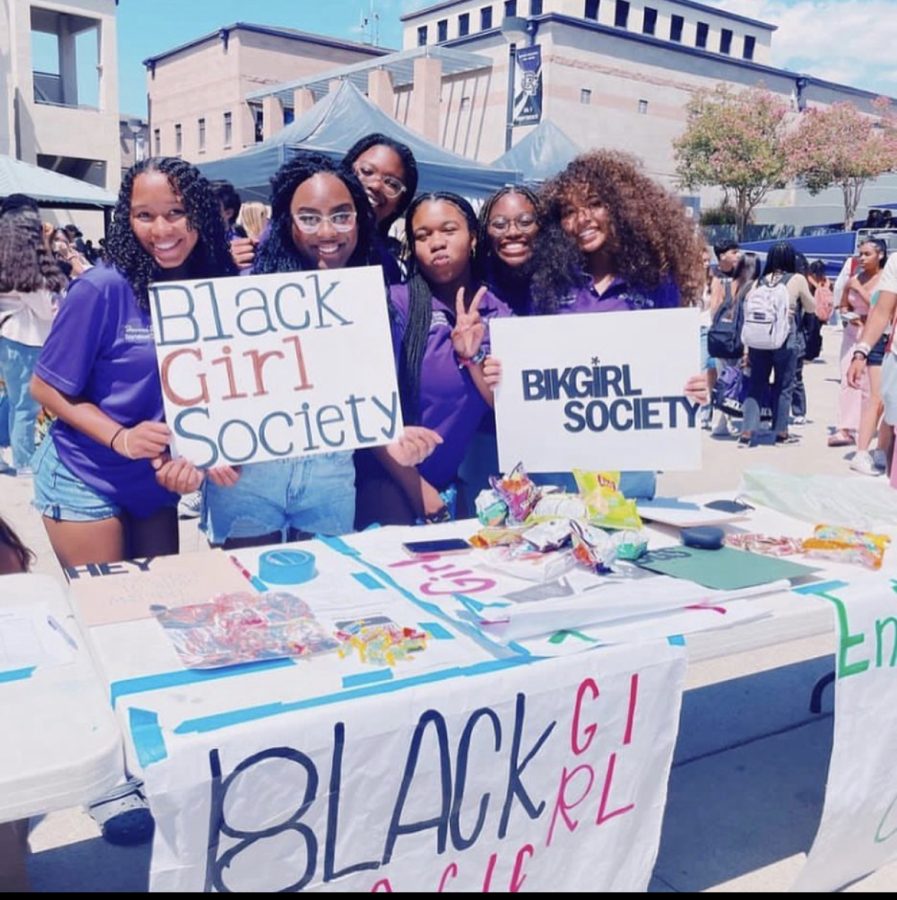 Black Girl Magic Club founders seniors Hannah Hawkins, Lyrique Wilson, and Secretary Gaelle Jean-Pierre  hold up signs with other club members to get people to come and sign up for the club!