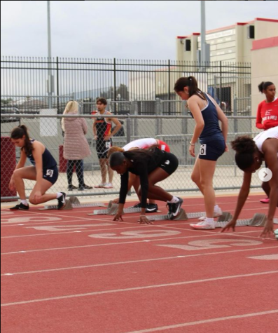 Caption: Members of the RCHS track team line up on the blocks to compete in a race. 