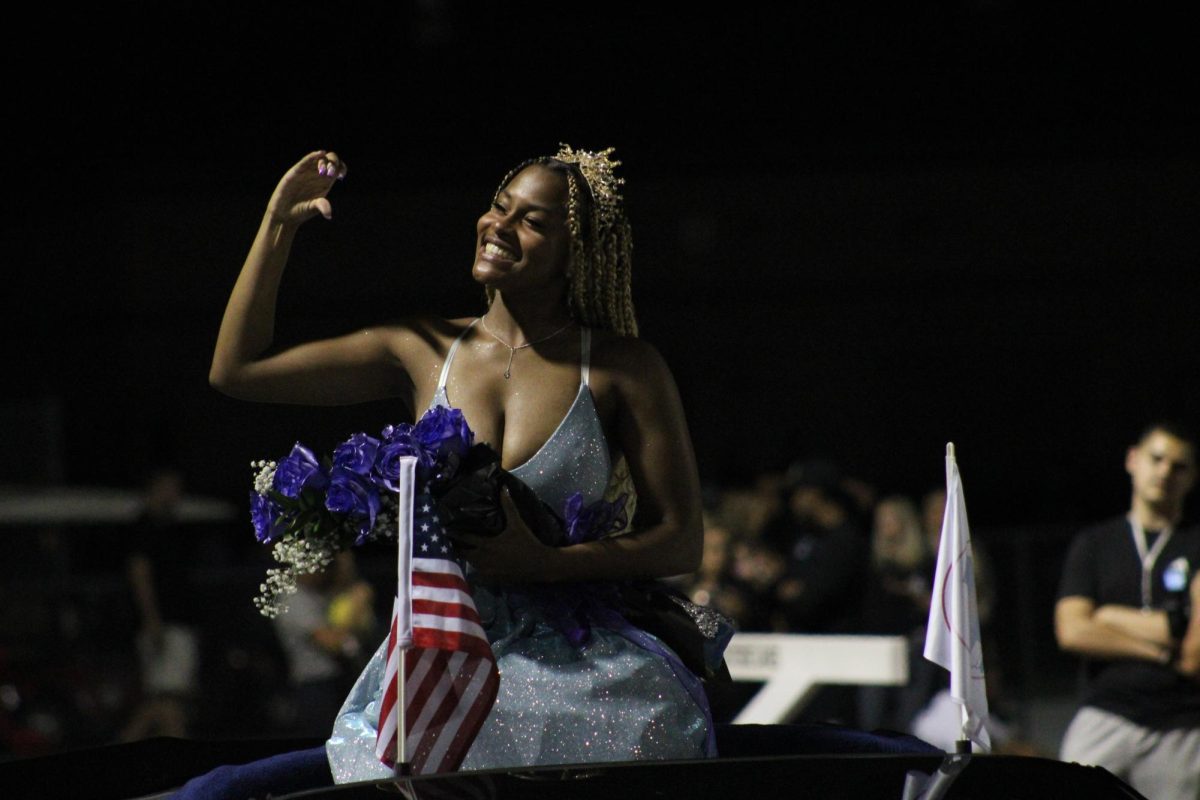 2022 Homecoming Queen Cassidy Brown holds up a heart to the crowd as they cheer her on.