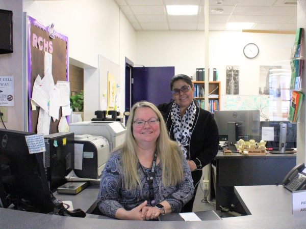 The two librarians, Connie Joyce & Sherrie Heinolle, sitting at the center desk in the front of the RCHS library.