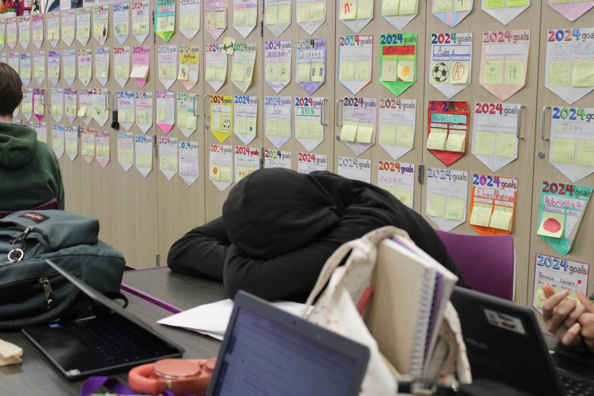 A student falls asleep during class, as their peers continue to work.
