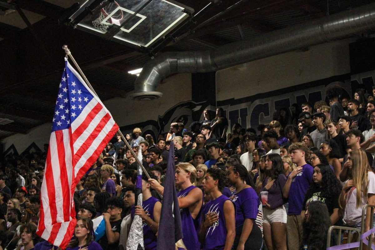  RCHS rooters holding a flag and standing for the Pledge of Allegiance with the senior class behind them. 