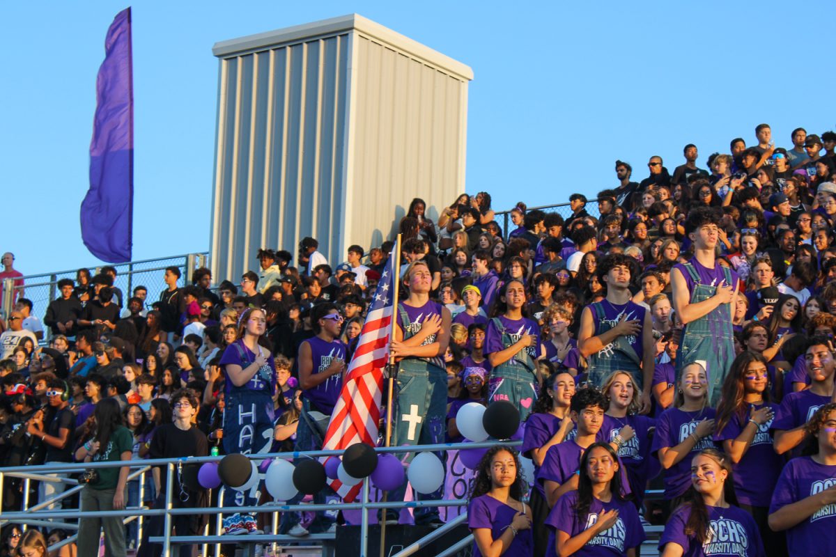 Members of the RCHS Rooters place their hands over their hearts during the National Anthem.