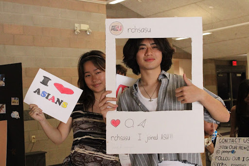 Two students from Asian Student Union pose for a photo with their club signs.