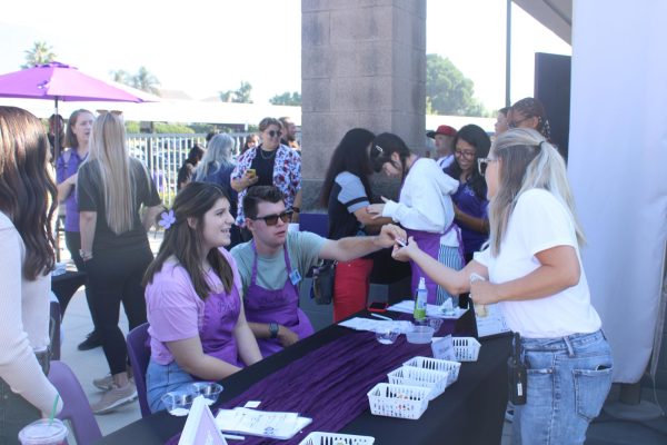 Junior Jolie Jenson and junior Evan Miles give a cup of coffee to a staff member at a Buddy's Brew event.