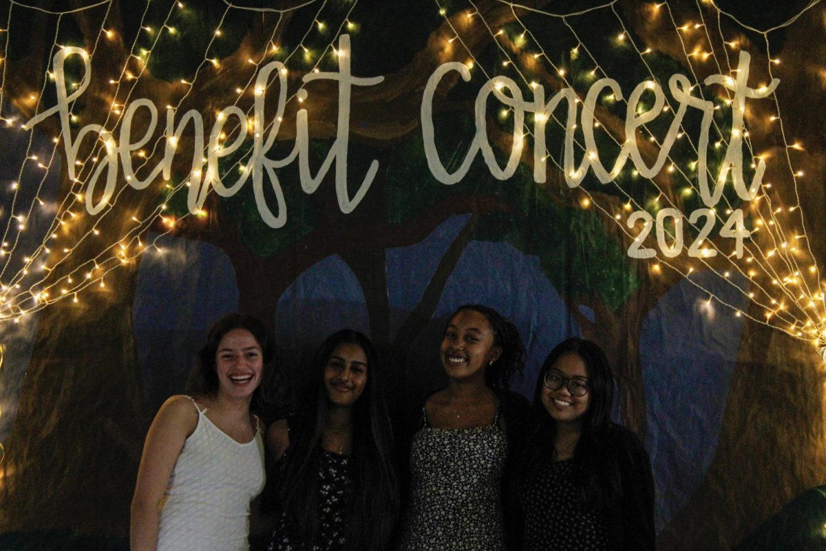 National Honors Society members posing in front of the benefit concert 2024 banner