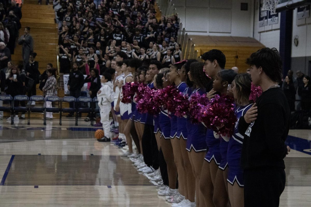 RCHS varsity cheer team places their hands over their hearts as the National Anthem is sung.  