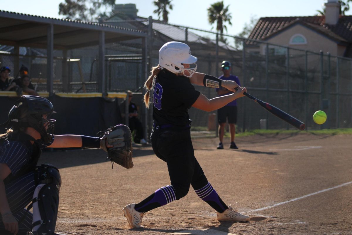 Sophomore Kinsey Komara hits the ball as the opposing team pitches to her.