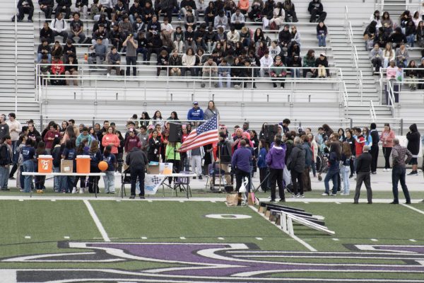 People stand during the singing of the national anthem before the start of the Cougar Relays. 
