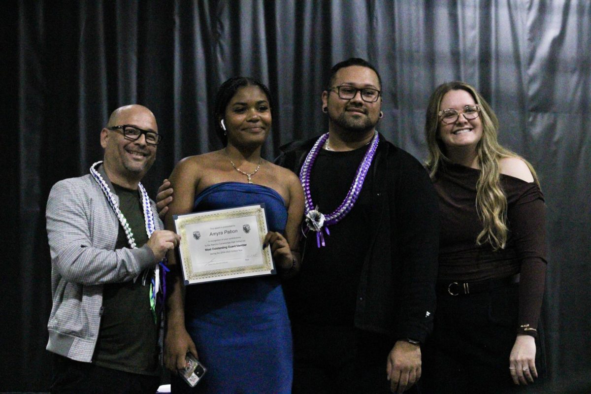 Junior, Amyra Pabon, smiles with her color guard instructors after being presented the "Most Outstanding Guard Member" award.
