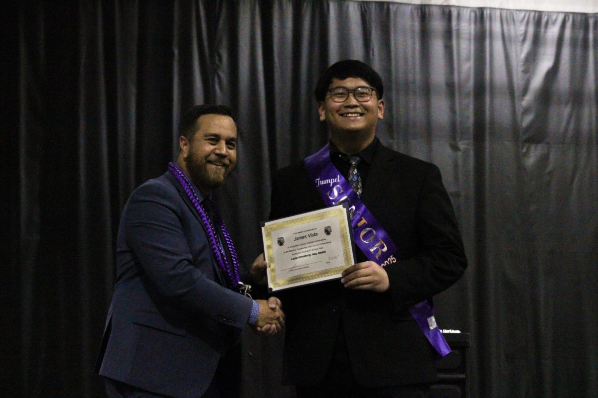 Senior, James Vista, is awarded the "Louis Armstrong" jazz award by Mr. Ana.