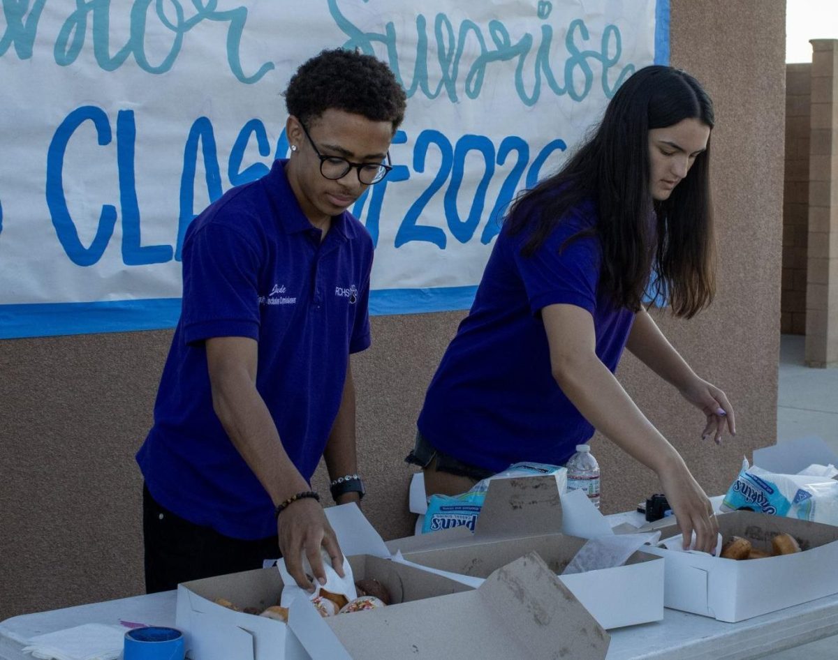  Juniors in ASB serve donuts to seniors as they walk into senior sunrise. Juniors had a chance to volunteer at senior sunrise to help serve donuts and coffee to seniors.