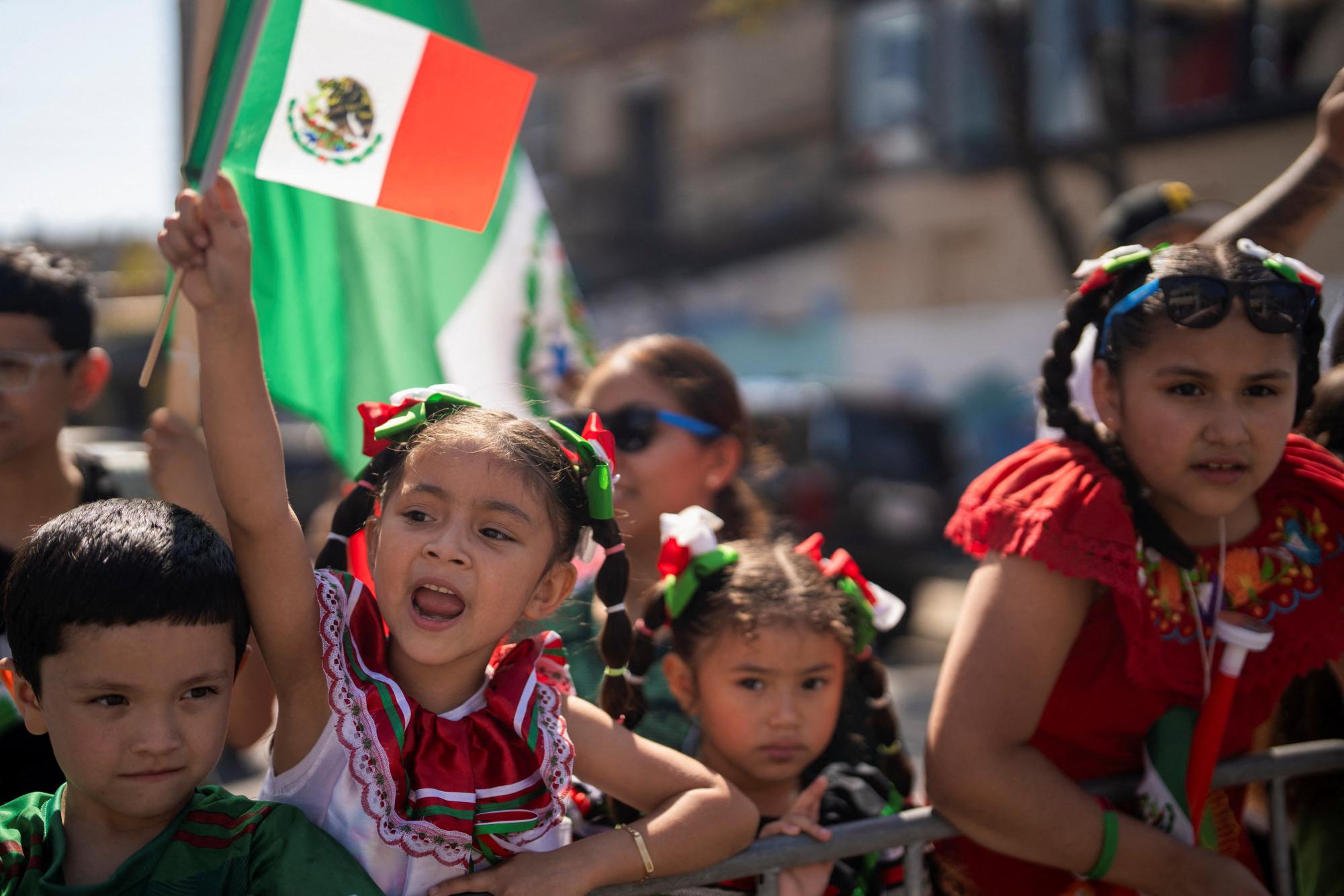 Mya Cortez, 6, waves to the floats during a Mexican Independence parade after U.S. President Donald Trump ordered increased federal law enforcement presence to assist in crime prevention, in Chicago, Illinois, U.S. September 14, 2025.  REUTERS/Audrey Richardson