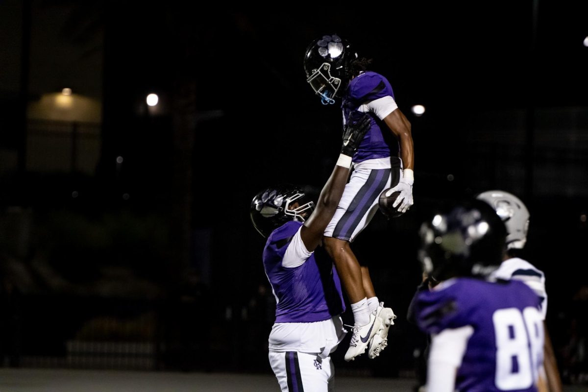 RCHS senior Malik White lifts up senior James Strong III after scoring a touchdown against Chaparral High School.