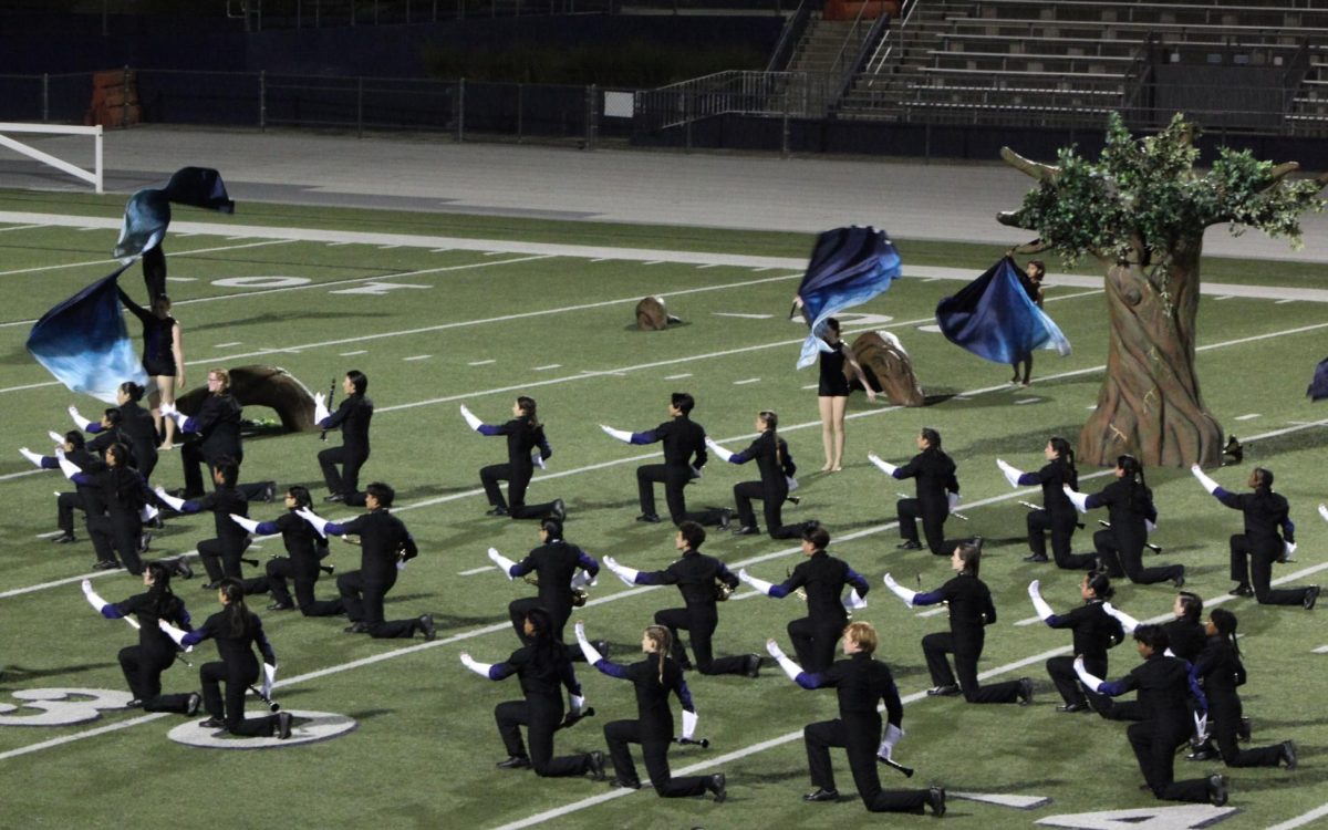Winds kneel while color guard spins their flags. 