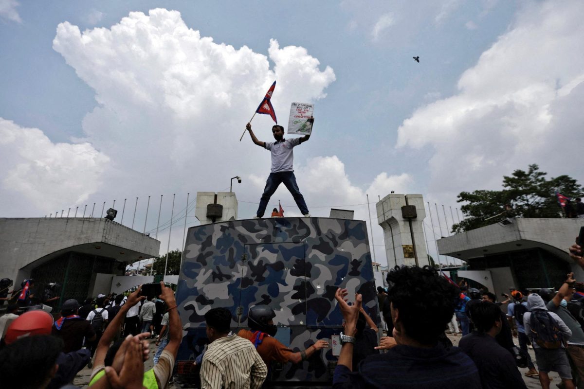 A demonstrator waves a flag as he stands atop a vehicle near the entrance of the Parliament during a protest against corruption and government’s decision to block several social media platforms, in Kathmandu, Nepal September 8, 2025. REUTERS/Navesh Chitrakar