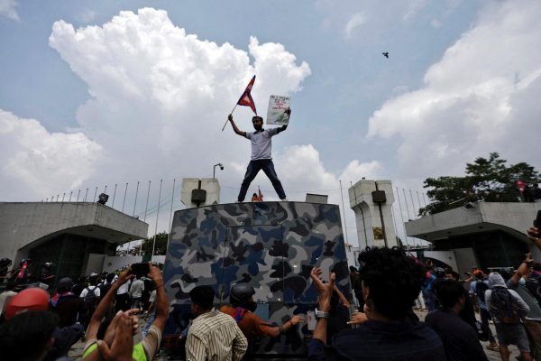 A demonstrator waves a flag as he stands atop a vehicle near the entrance of the Parliament during a protest against corruption and government’s decision to block several social media platforms, in Kathmandu, Nepal September 8, 2025. REUTERS/Navesh Chitrakar