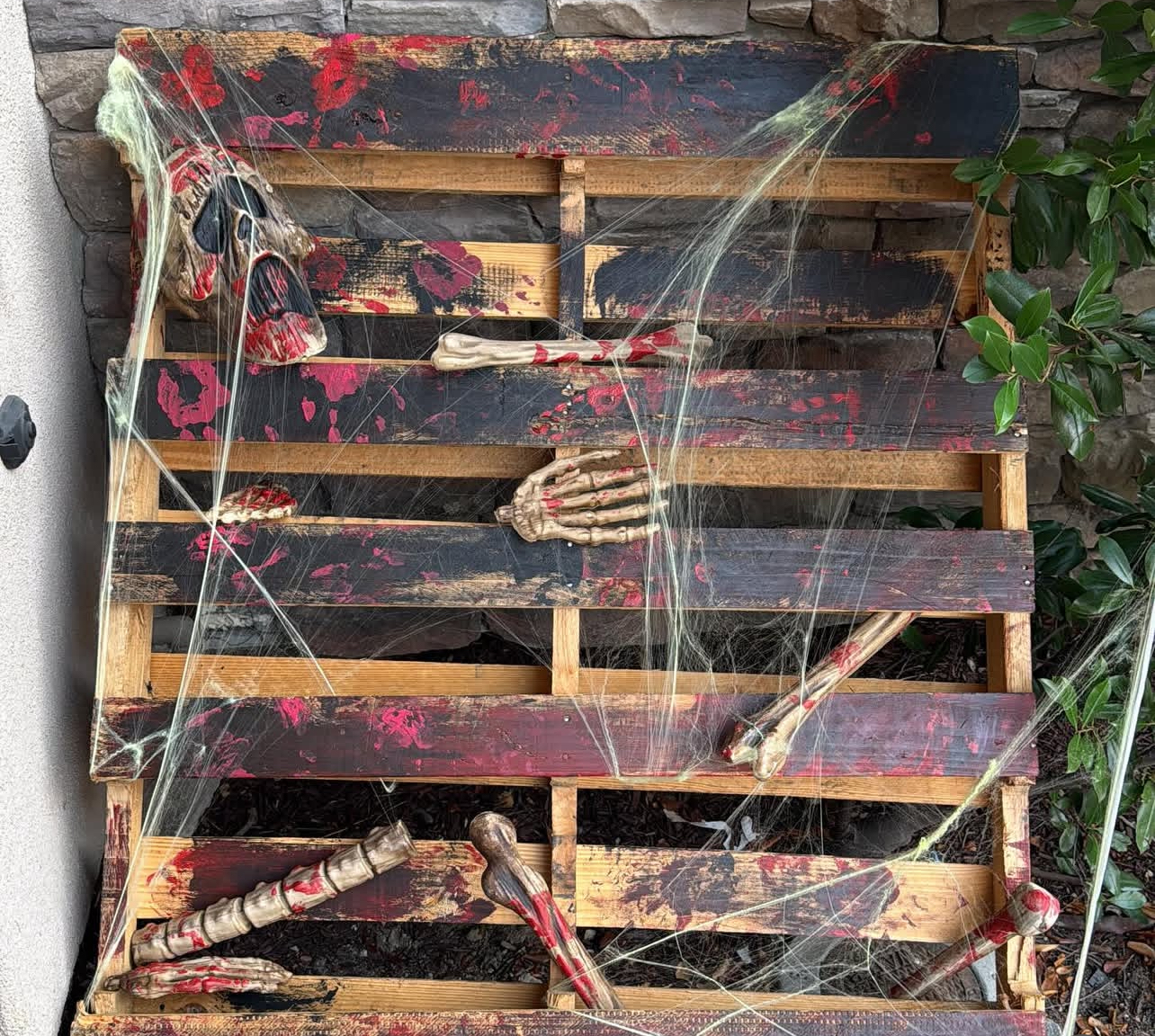 A house decoration with skeleton bones and spider webs covering a pallet board with red hand prints on it. Photo courtesy: Ms. Edith Perez-Kruchinsky