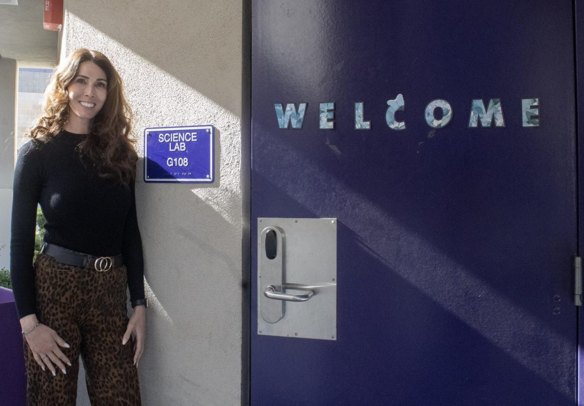 Mrs. Candice Newman stands by her classroom door with a welcoming smile. 