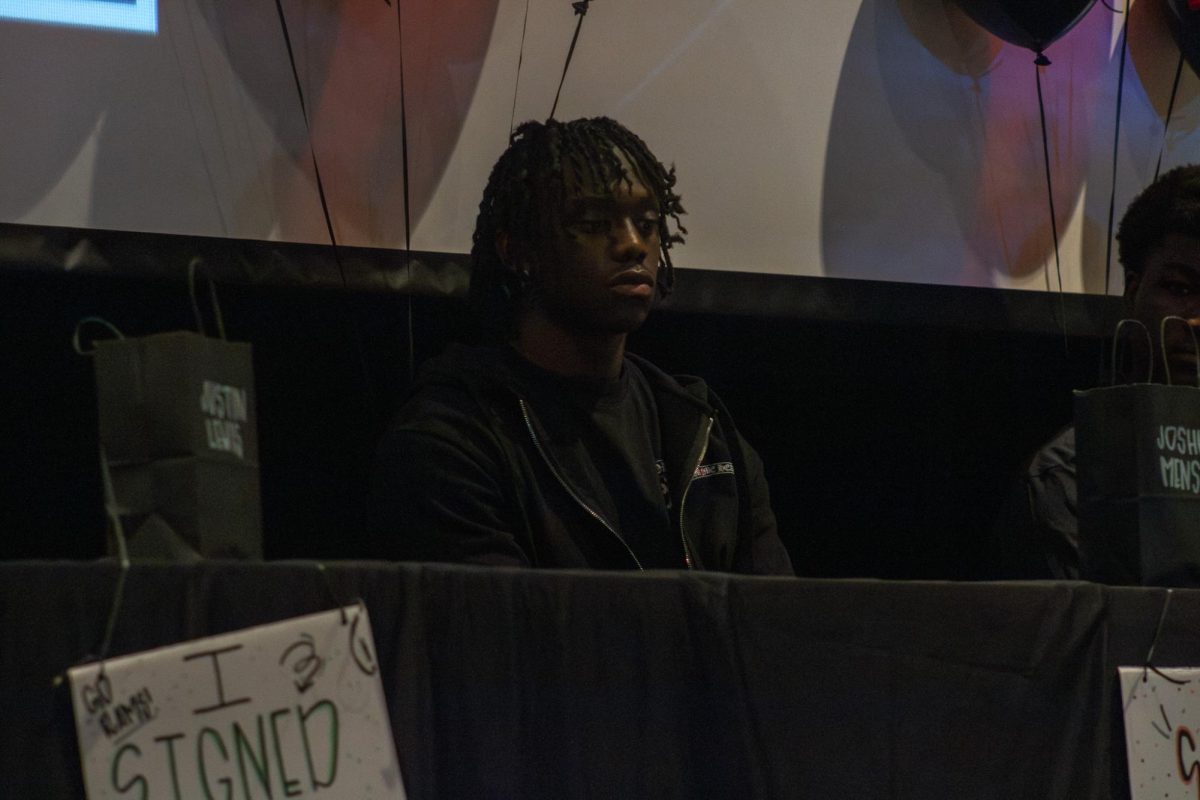 Joshua Mensa prepares to sign his commitment to New Mexico State