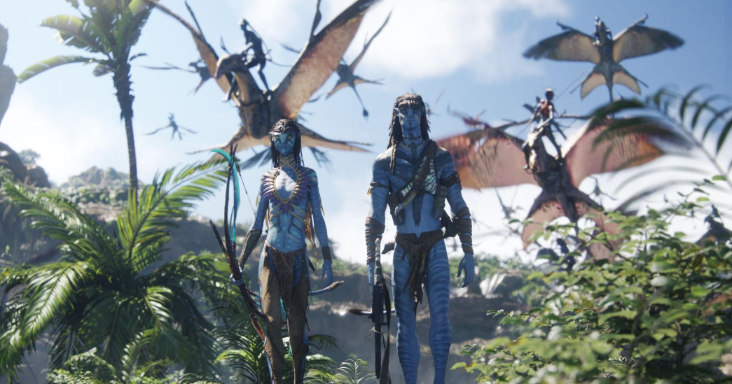 A concept photo of protagonists Neytiri (played by Zoe Saldaña) and Jake (played by Sam Worthington) walk toward the camera as other Na’vi fly behind them. Photo Courtesy: 20th Century Studios